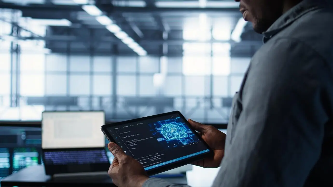 Крупный план специалиста по компьютерным наукам в дата-центре, использующего ИИ на планшете.